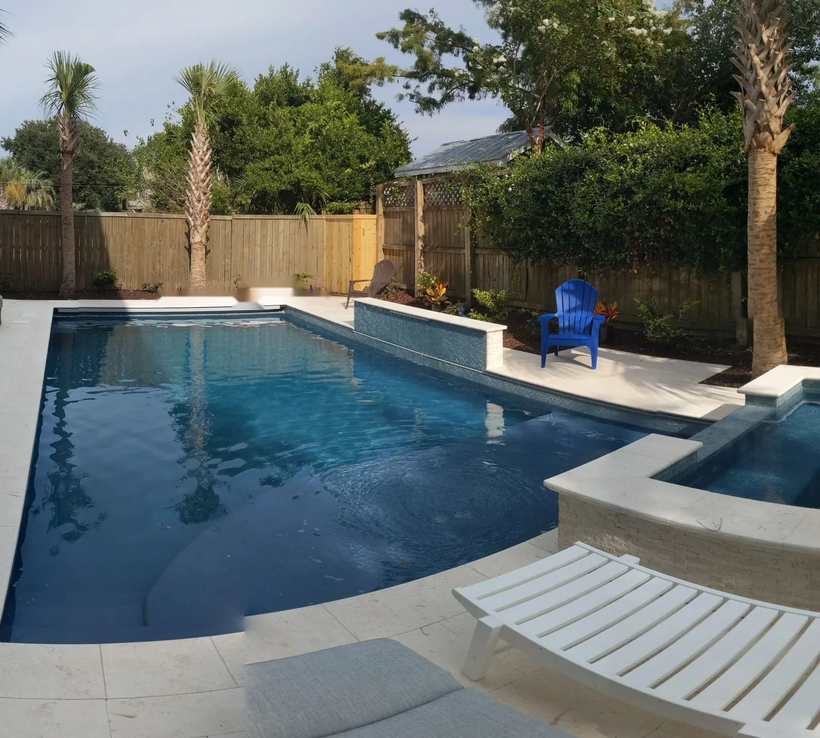 Long pool with a raised hot tub and loungers along the fence
